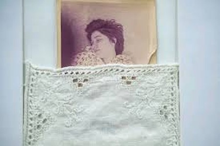 Objeto de la exhibición Los hilos de la Memoria: una fotografía antigua junto a un bordado.